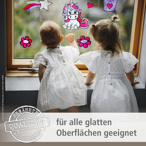 Zwei kleine Mädchen in weißen Kleidern blicken von hinten aus dem Fenster, das mit selbstgemachten Window Color Bildern (Einhorn, Blumen, Stern) dekoriert ist. Text im Bild: "Bewährte Qualität – Made in Germany. für alle glatten Oberflächen geeignet".